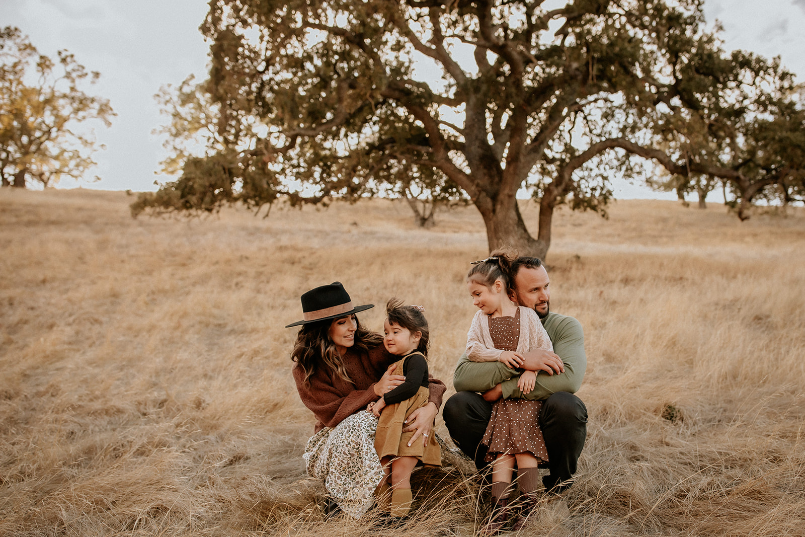 Lifestyle family photography session family wears boho clothes in front of oak tree