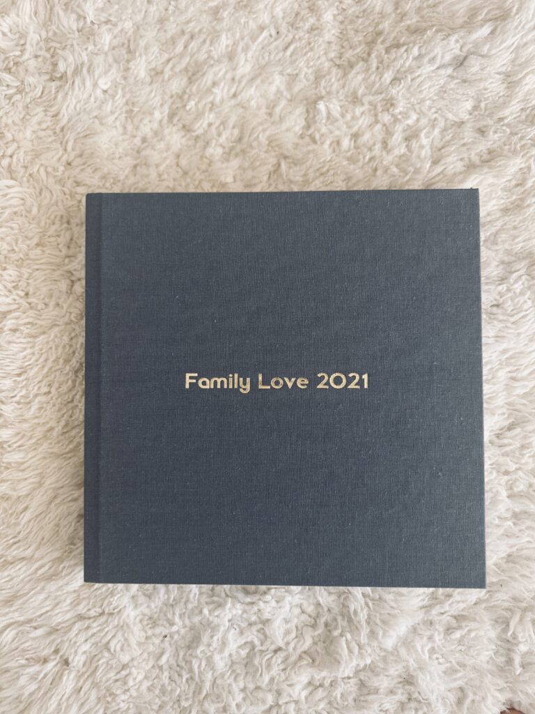 A gray photo album with the title of 'Family Love 2021' in gold lettering. Print product designed by Ashley Kaplan Photography 