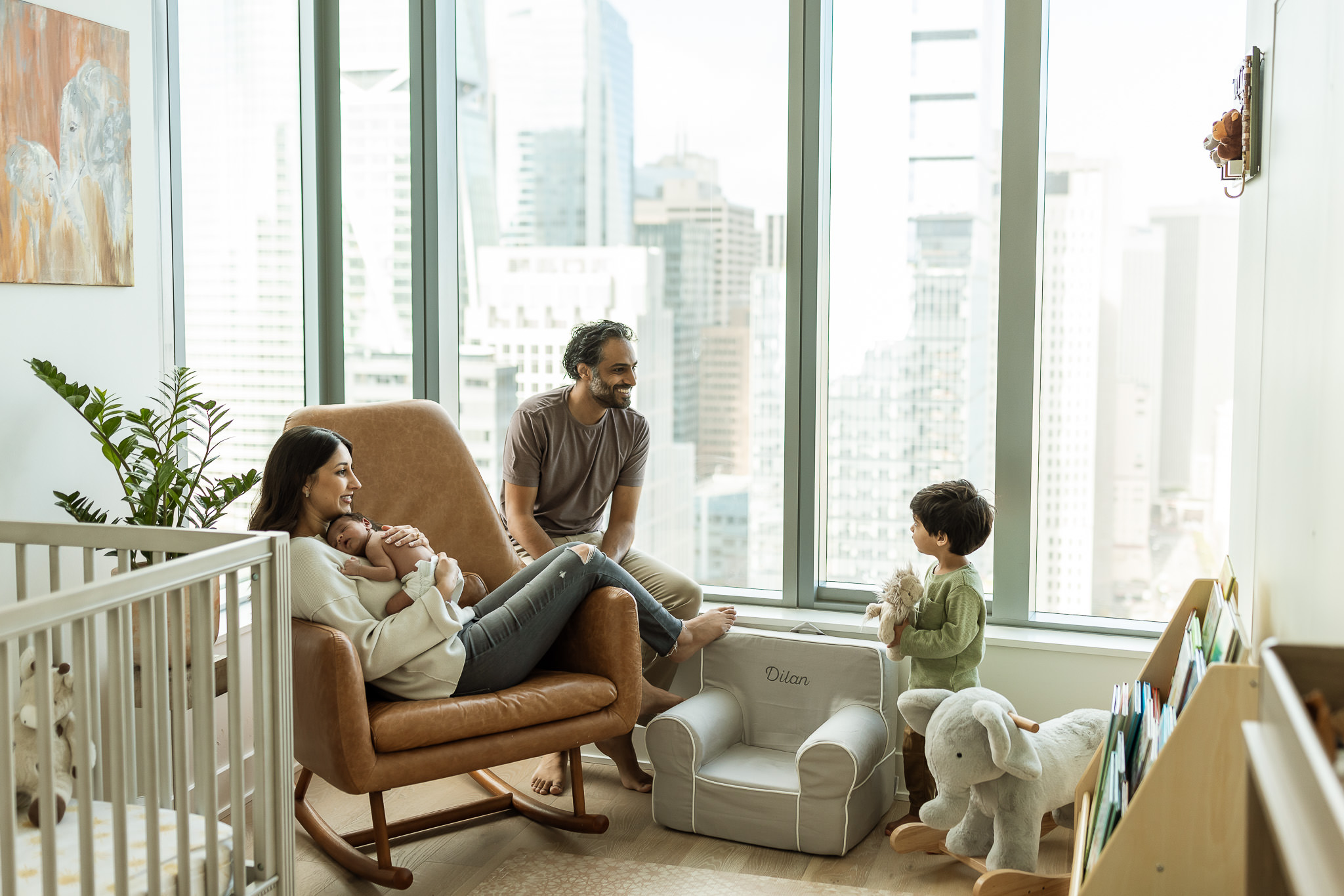 Photo of parents and sibling with baby in nursery at in home lifestyle newborn session with Ashley Kaplan Photography