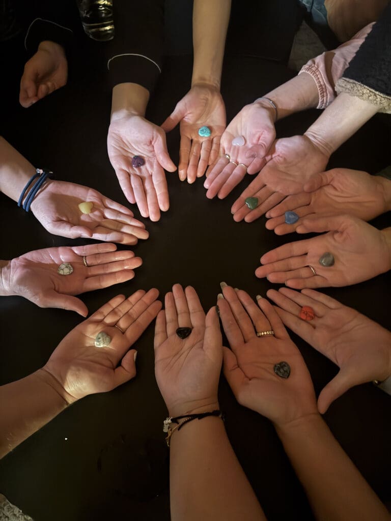 12 hands holding heart stones meet in a circle at Finding Heart Workshop for photographers
