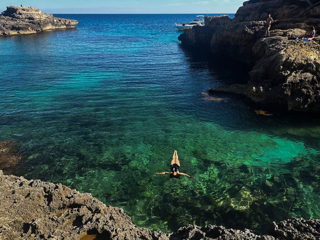 Women floating on her bag in tropical green-blue waters 