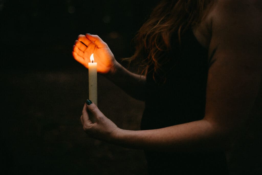 Dark and moody photos cropped just showing a woman's hands holding a lit candle